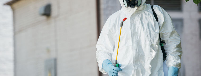 pest control worker in respirator holding sprayer